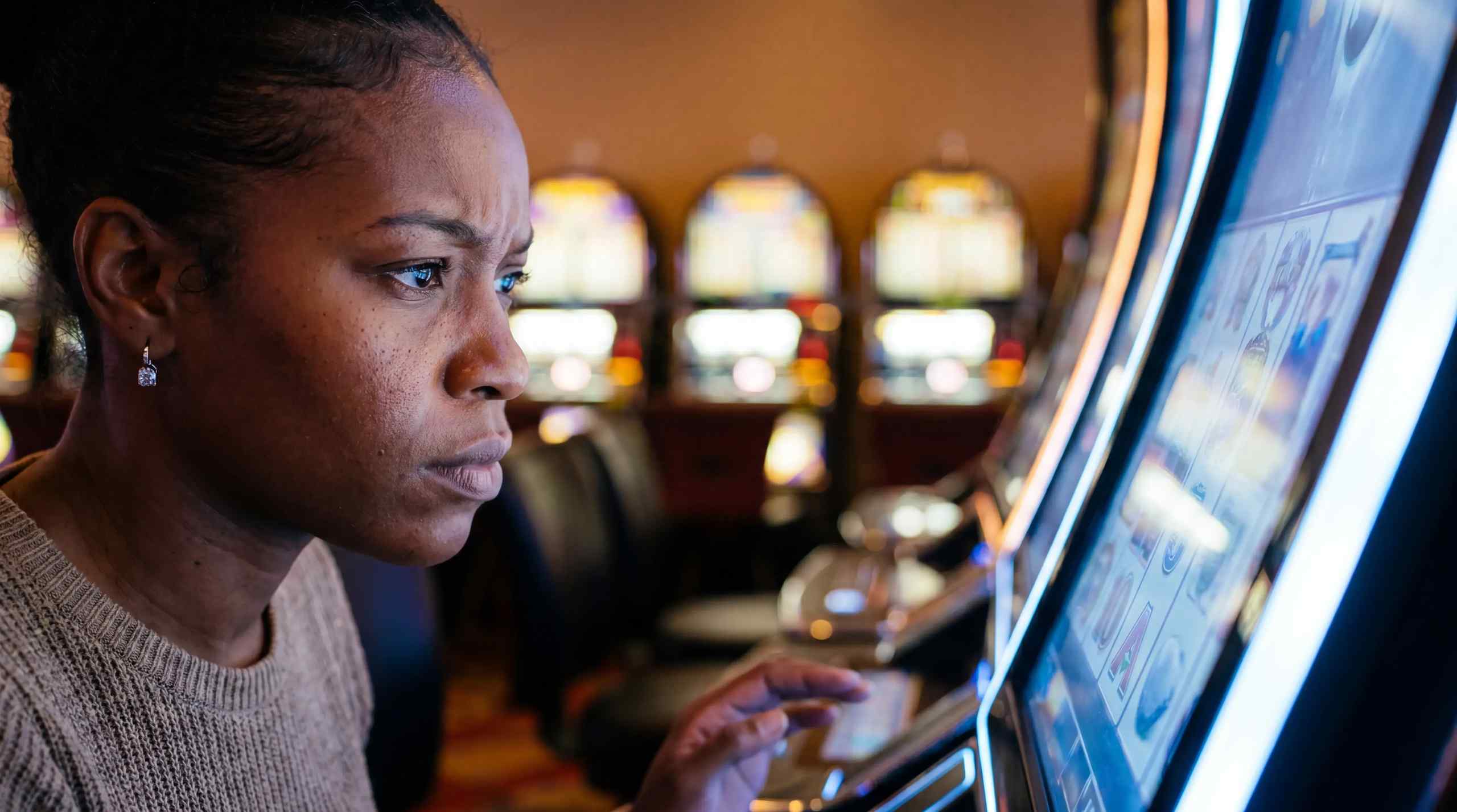 A woman looks confused by a slot machine.